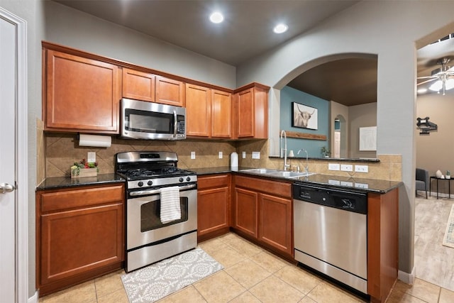 kitchen with appliances with stainless steel finishes, sink, dark stone counters, and decorative backsplash