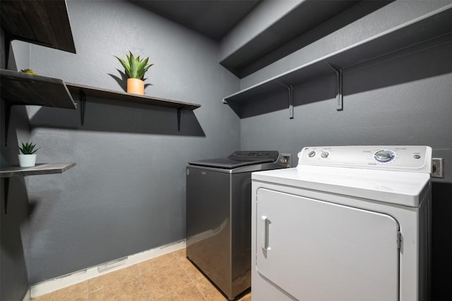 laundry area with washing machine and dryer and light tile patterned floors