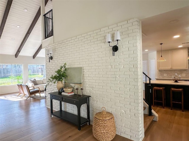 living room featuring wood-type flooring, high vaulted ceiling, wooden ceiling, brick wall, and beam ceiling