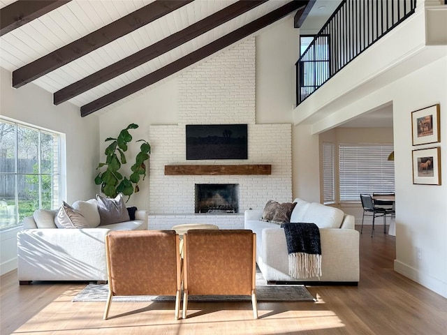 living room featuring hardwood / wood-style floors, beam ceiling, a fireplace, and high vaulted ceiling