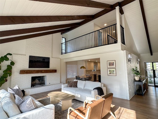 living room featuring hardwood / wood-style flooring, lofted ceiling with beams, and a brick fireplace