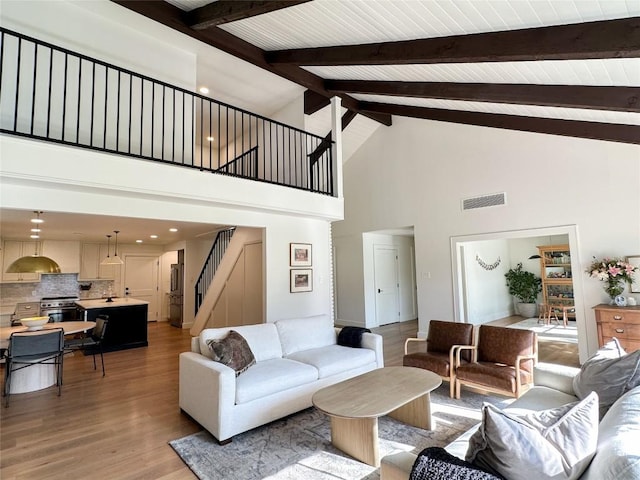 living room featuring vaulted ceiling with beams and light hardwood / wood-style floors