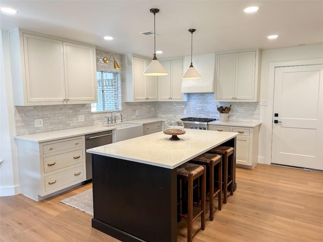 kitchen featuring stainless steel dishwasher, sink, a kitchen island, and white cabinets