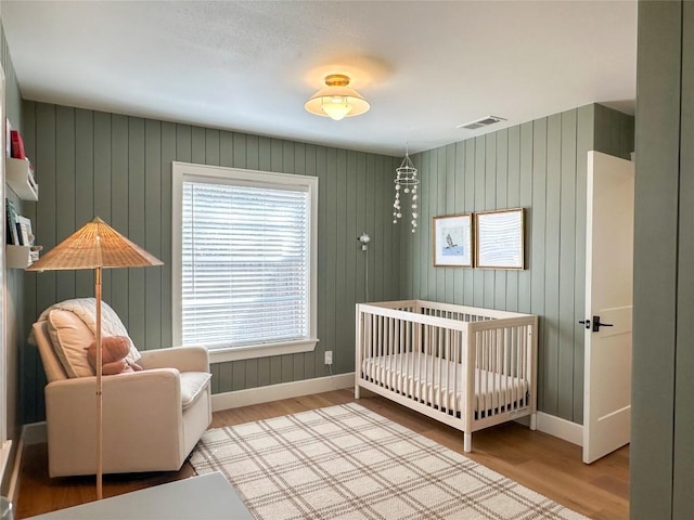 bedroom featuring a nursery area and light hardwood / wood-style floors