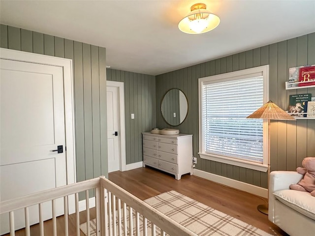 bedroom featuring wood-type flooring and a nursery area