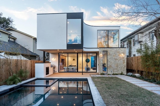 back house at dusk featuring a fenced in pool and a patio area