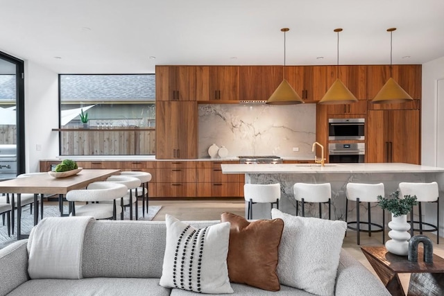 kitchen with sink, a breakfast bar area, backsplash, and decorative light fixtures