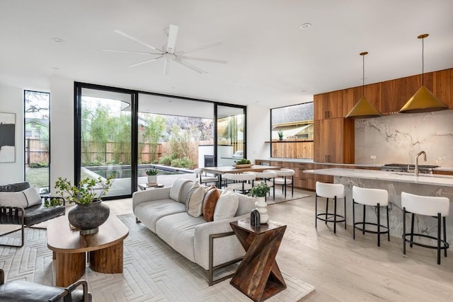 living room with a wall of windows, sink, and light wood-type flooring