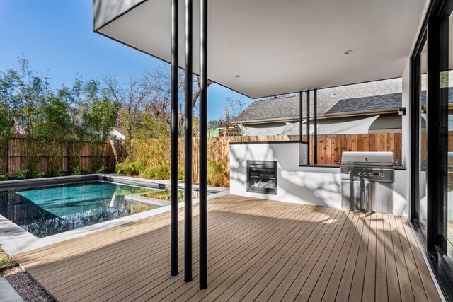 deck featuring a fenced in pool, an outdoor kitchen, and area for grilling