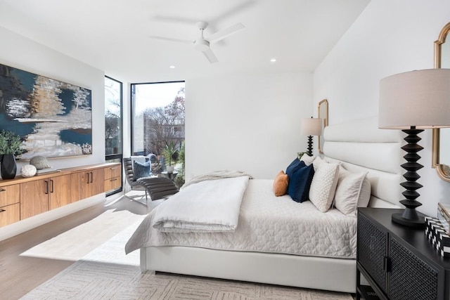 bedroom with expansive windows, ceiling fan, and light wood-type flooring