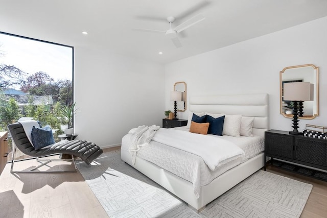 bedroom with a wall of windows, light hardwood / wood-style floors, and ceiling fan