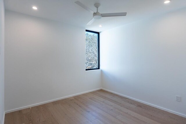 spare room with ceiling fan and light wood-type flooring