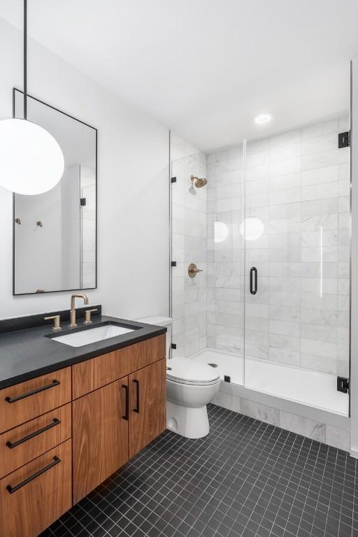 bathroom featuring vanity, tile patterned flooring, a shower with door, and toilet