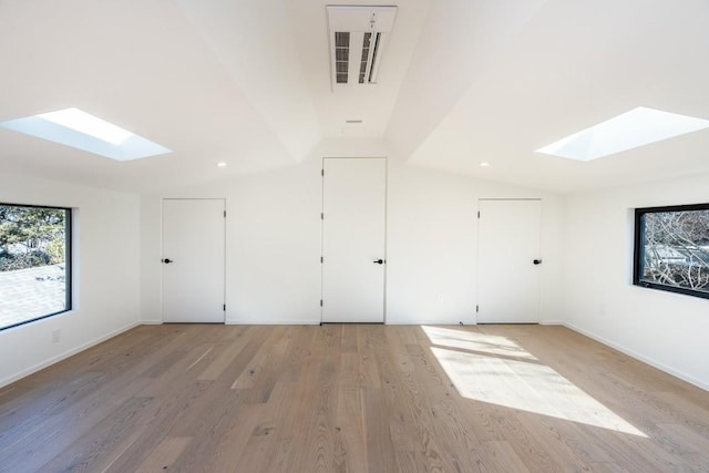 additional living space with vaulted ceiling with skylight and light hardwood / wood-style floors