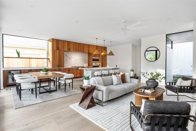 living room with floor to ceiling windows, wood walls, ceiling fan, and light hardwood / wood-style flooring