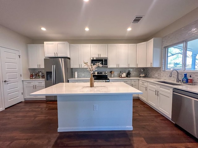 kitchen with stainless steel appliances, a center island, sink, and white cabinets