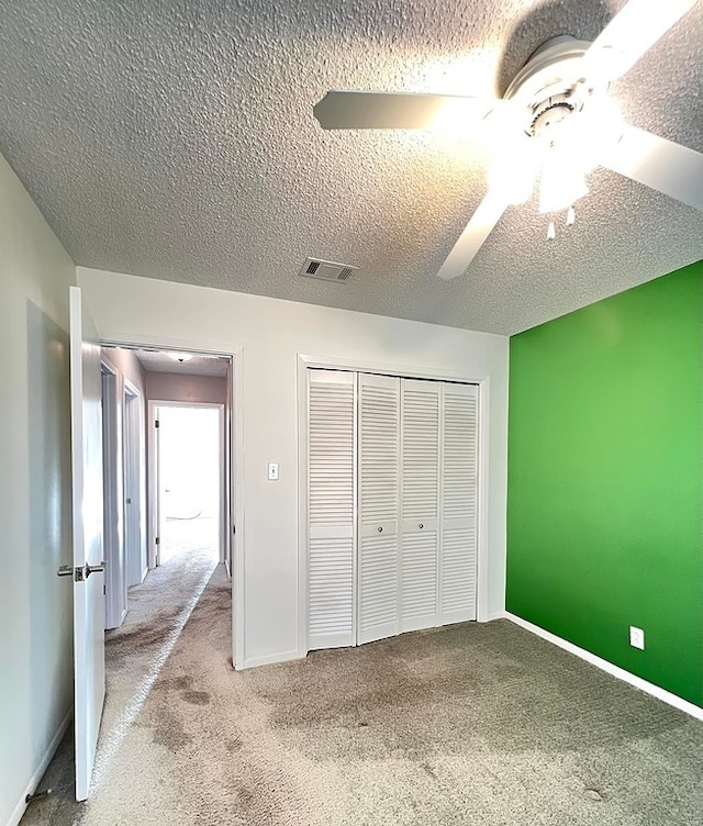 unfurnished bedroom with ceiling fan, light colored carpet, a closet, and a textured ceiling