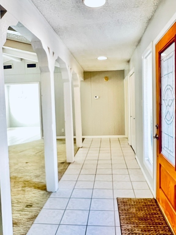 hall featuring a textured ceiling and light tile patterned floors