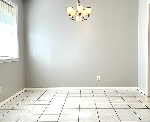 tiled spare room with an inviting chandelier