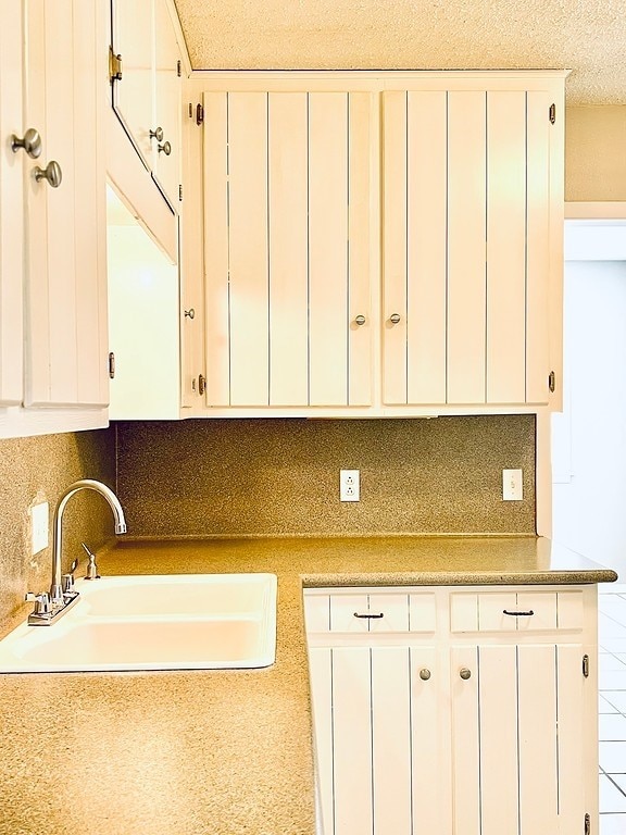 kitchen featuring tasteful backsplash, sink, and white cabinets