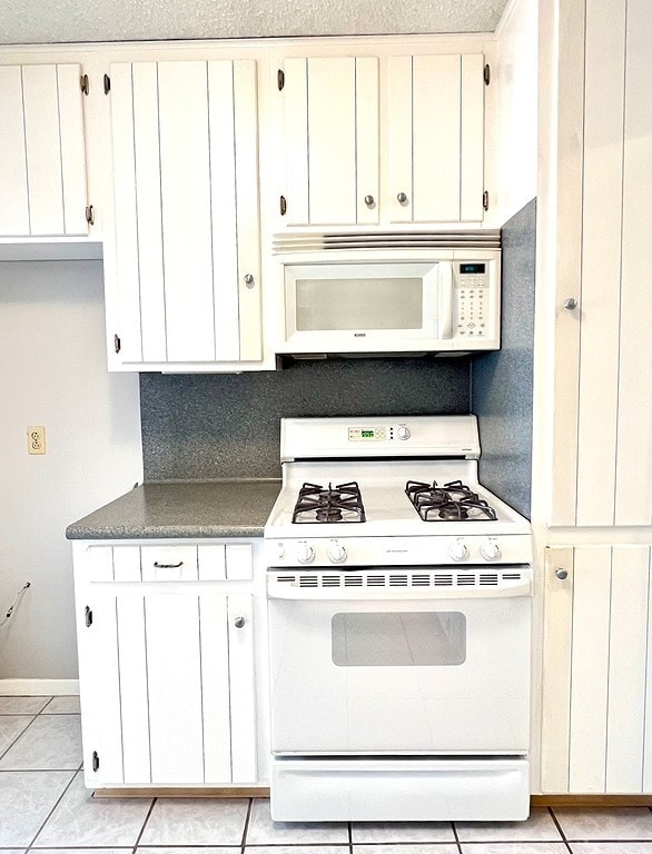 kitchen featuring light tile patterned floors, white cabinets, and white appliances