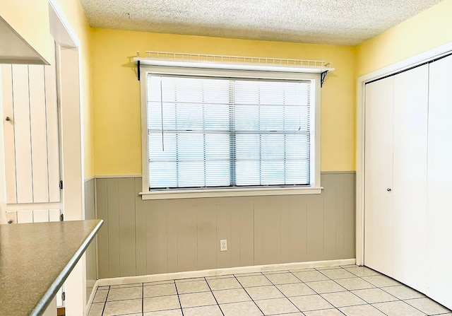 interior space with light tile patterned floors, white cabinets, and a textured ceiling