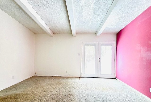 carpeted spare room with beamed ceiling, a textured ceiling, and french doors