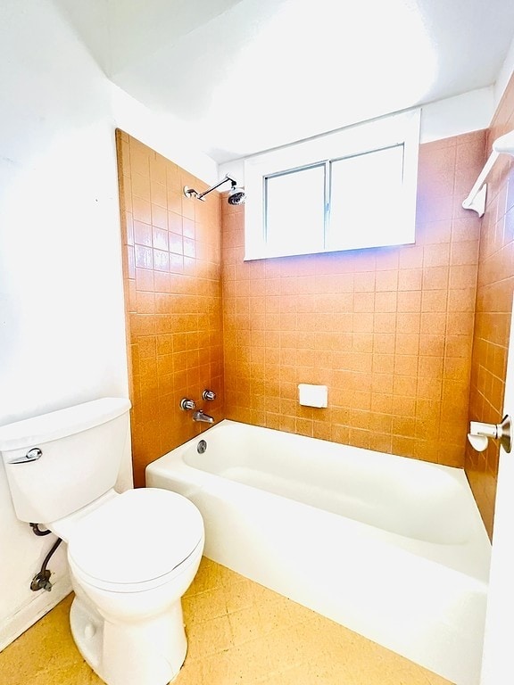 bathroom featuring tiled shower / bath combo and toilet