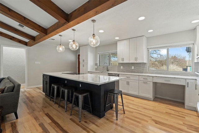 kitchen featuring pendant lighting, white cabinetry, a breakfast bar area, decorative backsplash, and a center island