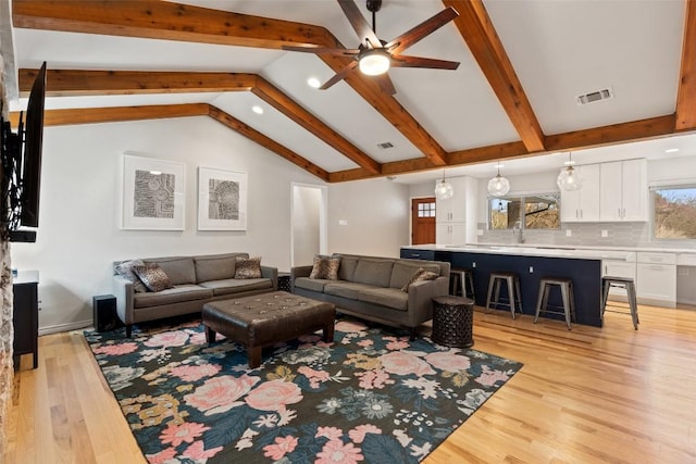 living room featuring ceiling fan, lofted ceiling with beams, and light wood-type flooring