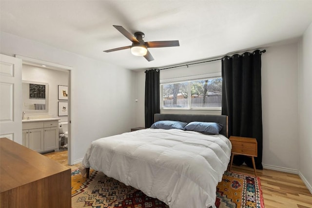 bedroom with connected bathroom, light hardwood / wood-style flooring, sink, and ceiling fan