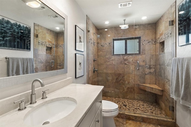 bathroom featuring vanity, a shower with door, and toilet