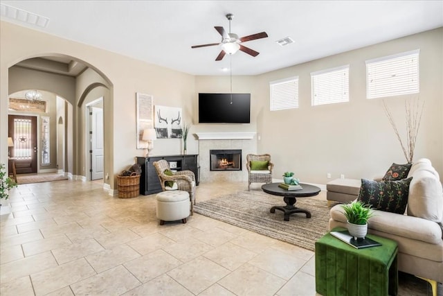 living room featuring a tiled fireplace and ceiling fan