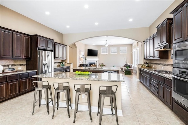 kitchen featuring dark brown cabinets, stainless steel appliances, a kitchen breakfast bar, and a kitchen island