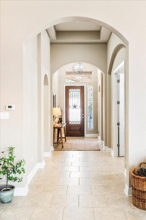 tiled foyer with a raised ceiling and a high ceiling