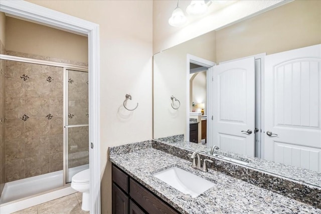 bathroom with tile patterned flooring, vanity, a shower with shower door, and toilet