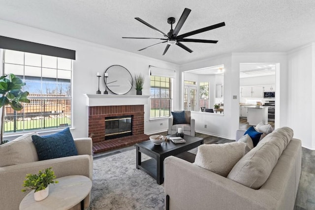 living room with hardwood / wood-style flooring, crown molding, a brick fireplace, and a textured ceiling