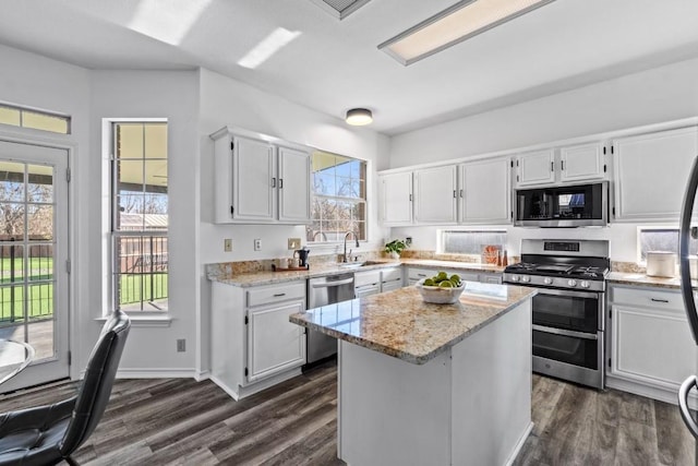 kitchen featuring sink, stainless steel appliances, light stone countertops, white cabinets, and a kitchen island