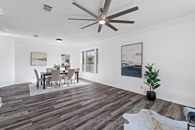 dining room with ceiling fan, crown molding, dark wood-type flooring, and a textured ceiling