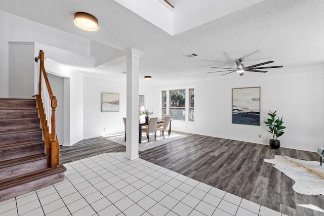 interior space with ceiling fan, tile patterned flooring, a textured ceiling, and ornate columns