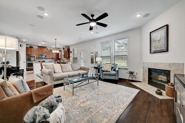 living room featuring ceiling fan, a fireplace, and dark hardwood / wood-style floors