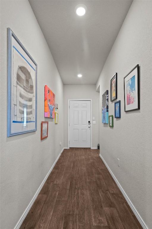 hallway featuring dark wood-style floors and baseboards