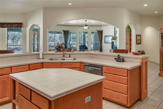 kitchen with light tile patterned flooring, sink, dishwasher, a kitchen island, and ceiling fan