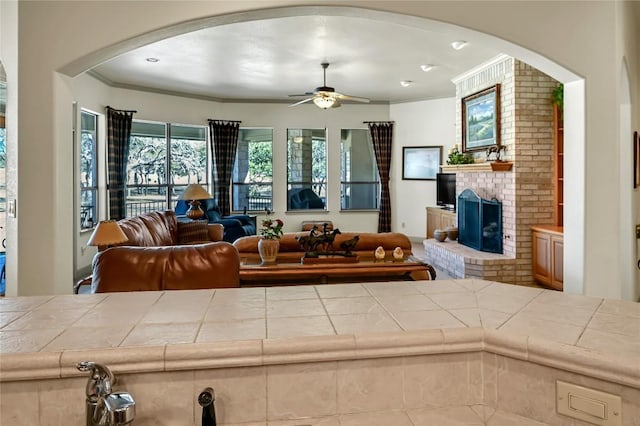 living room featuring a fireplace, ornamental molding, and ceiling fan