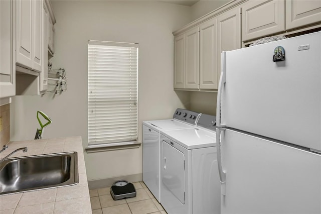 clothes washing area featuring cabinets, sink, washer and dryer, and light tile patterned floors