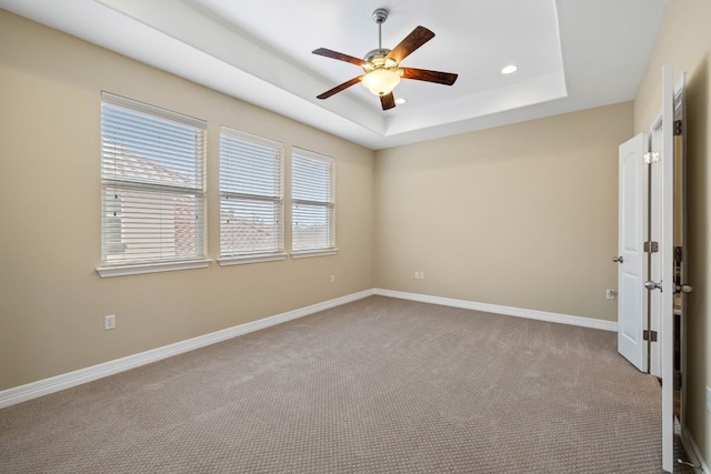 carpeted empty room with ceiling fan and a tray ceiling