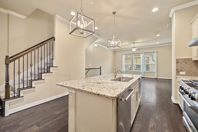 kitchen featuring appliances with stainless steel finishes, decorative light fixtures, white cabinetry, sink, and a kitchen island with sink