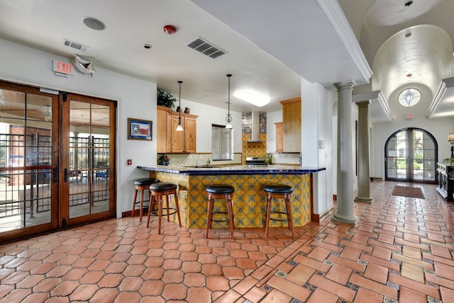 kitchen with backsplash, french doors, a breakfast bar area, and ornate columns