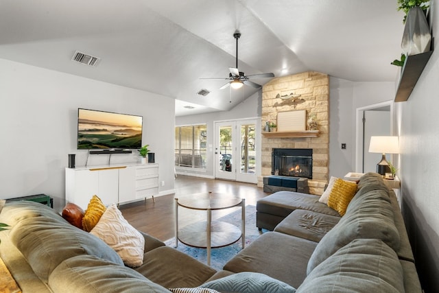 living area featuring visible vents, a ceiling fan, lofted ceiling, wood finished floors, and a stone fireplace