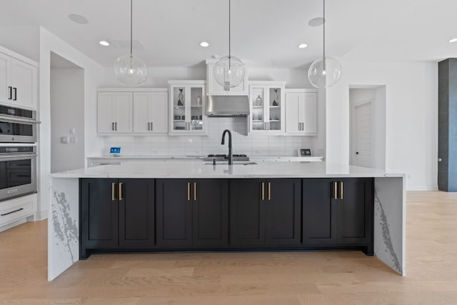 kitchen featuring decorative light fixtures and a large island with sink